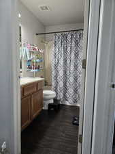 Full bathroom with vanity, hardwood / wood-style floors, shower / tub combo, and toilet