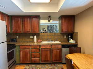 Kitchen featuring tile counter and backsplash, sink, stainless steel range with electric top, white fridge, and a dining table