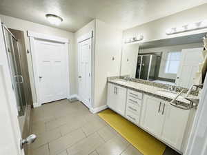 Master bathroom featuring a textured ceiling, a shower with shower door, and vanity