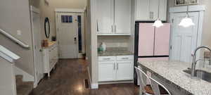 Kitchen featuring pendant lighting, white cabinetry, sink, dark hardwood / wood-style flooring, and white refrigerator