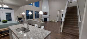 Kitchen featuring hanging light fixtures, sink, a center island with sink, and light stone counters