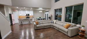 Living room featuring dark wood-type flooring, an inviting chandelier, and a towering ceiling