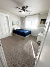 Bedroom featuring ceiling fan, carpet floors, and a textured ceiling