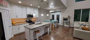 Kitchen featuring white cabinetry, sink, stainless steel appliances, and hanging light fixtures