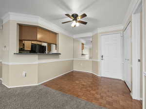 Kitchen with black fridge, parquet floors, ornamental molding, kitchen peninsula, and ceiling fan