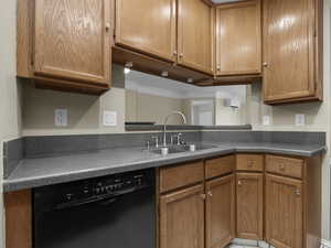 Kitchen featuring crown molding, black dishwasher, and sink