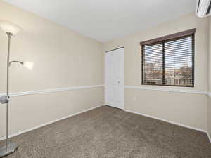 Unfurnished bedroom featuring an AC wall unit and carpet floors