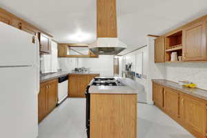 Kitchen featuring island exhaust hood, white appliances, and center island