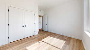 Unfurnished bedroom featuring a closet and light hardwood / wood-style flooring