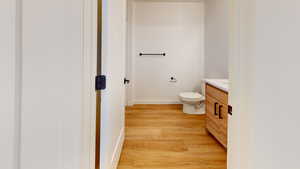 Bathroom featuring hardwood / wood-style flooring, toilet, and vanity