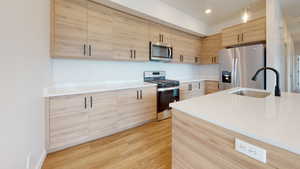 Kitchen featuring sink, appliances with stainless steel finishes, light brown cabinets, and pendant lighting