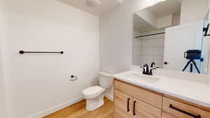 Bathroom featuring hardwood / wood-style flooring, vanity, toilet, and a shower