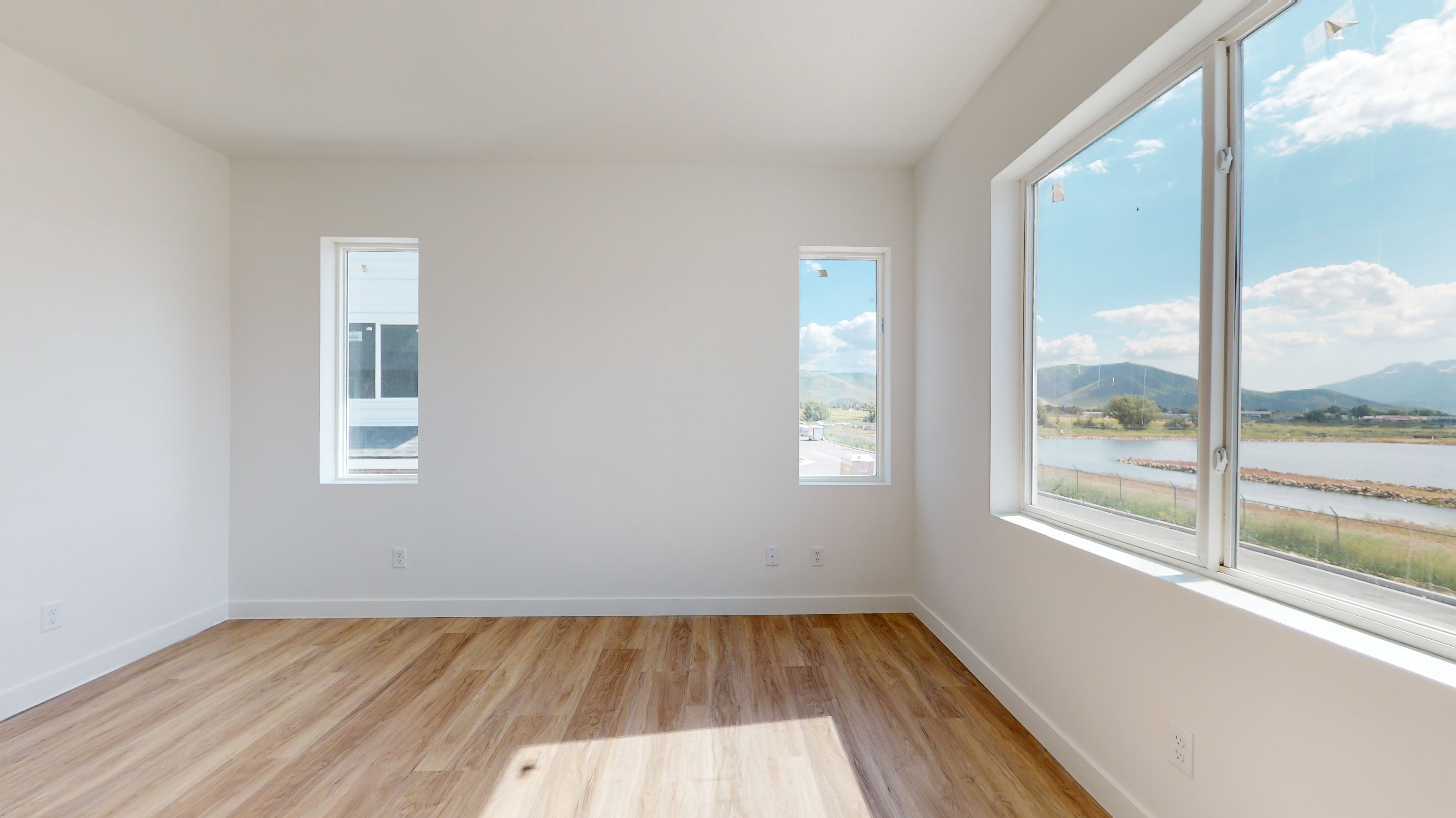Empty room with light hardwood / wood-style floors and a water and mountain view