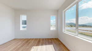 Empty room with light hardwood / wood-style floors and a water and mountain view