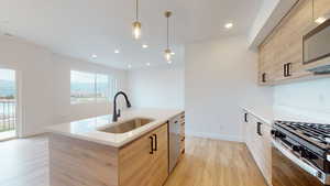 Kitchen featuring sink, appliances with stainless steel finishes, hanging light fixtures, and light brown cabinetry