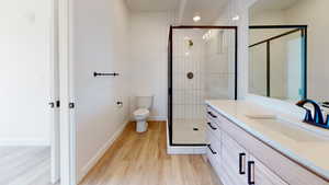 Bathroom with wood-type flooring, an enclosed shower, vanity, and toilet