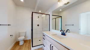 Bathroom featuring toilet, an enclosed shower, vanity, and wood-type flooring