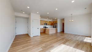 Unfurnished living room with a chandelier and light hardwood / wood-style flooring