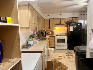 Kitchen with white appliances, sink, and light brown cabinetry