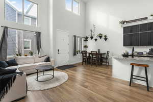 Living room with a towering ceiling, sink, and light hardwood / wood-style flooring