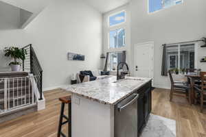 Kitchen featuring stainless steel dishwasher, sink, a center island with sink, and light wood-type flooring