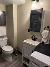 Bathroom with vanity, hardwood / wood-style floors, toilet, and washer / dryer