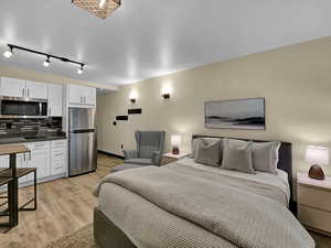 Bedroom with light hardwood / wood-style flooring and stainless steel fridge