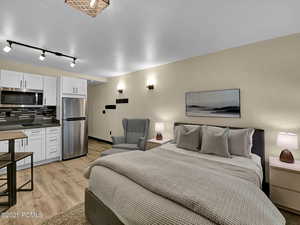 Bedroom with light hardwood / wood-style flooring and stainless steel refrigerator