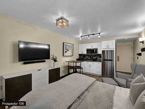 Bedroom featuring stainless steel fridge and wood-type flooring