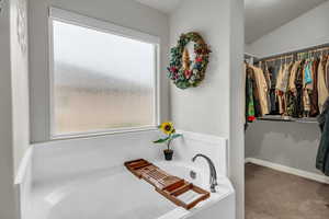 Bathroom with vaulted ceiling and a tub to relax in