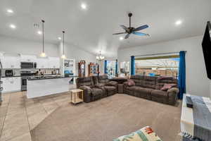 Tiled living room with sink, high vaulted ceiling, and ceiling fan with notable chandelier