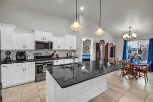 Kitchen with appliances with stainless steel finishes, sink, white cabinets, and a center island with sink