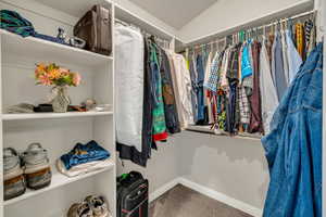 Spacious closet with lofted ceiling and carpet flooring