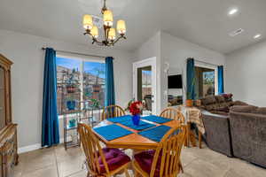 Tiled dining area featuring lofted ceiling, a chandelier, and a wealth of natural light