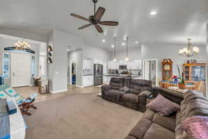 Living room featuring sink, ceiling fan with notable chandelier, vaulted ceiling, and light tile patterned floors