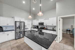 Kitchen featuring sink, white cabinets, stainless steel appliances, and an island with sink