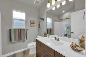 Bathroom with tile patterned floors, curtained shower, toilet, vaulted ceiling, and vanity