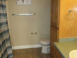 Bathroom with toilet, vanity, tile patterned flooring, and a shower with curtain