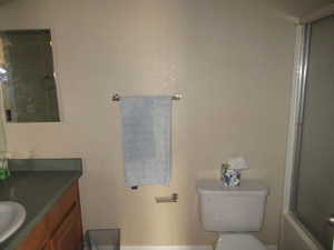 Full bathroom featuring toilet, combined bath / shower with glass door, and vanity