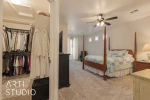 large primary bedroom with ceiling fan, light colored carpet, and a huge walk-in closet