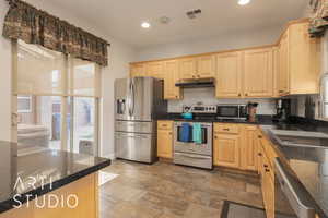 Kitchen with appliances with stainless steel finishes, dark granite counters