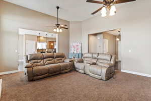 Carpeted living room with a high ceiling and ceiling fan