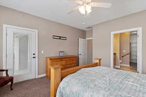 Bedroom with ceiling fan, light colored carpet, and ensuite bathroom