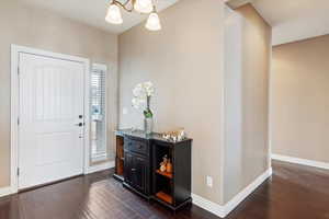 Foyer with dark hardwood / wood-style floors and an inviting chandelier