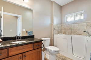 Bathroom with toilet, tile patterned floors, a bathtub, and vanity