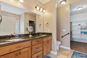 Bathroom with toilet, vanity, tile patterned flooring, and a shower with shower door