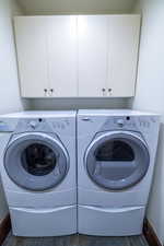 Laundry room featuring cabinets, dark hardwood / wood-style flooring, and washer and clothes dryer