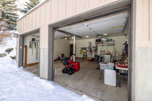 Snow covered garage featuring a garage door opener