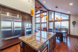 Kitchen with built in appliances, light stone countertops, a center island, dark hardwood / wood-style flooring, and wine cooler