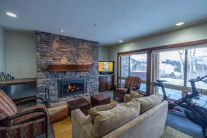 Living room featuring a stone fireplace, light carpet, and a textured ceiling